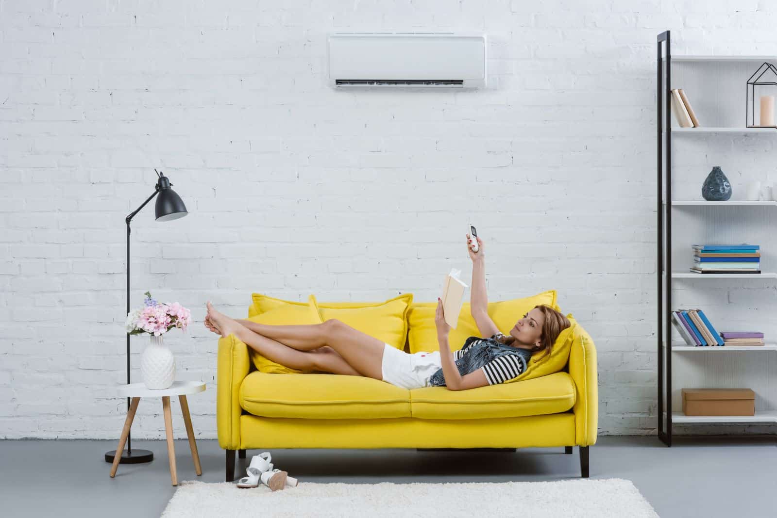 young woman lying on yellow couch enjoying air conditioning